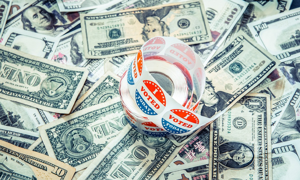 Roll of I VOTED stickers sits atop a pile of dollar bills to illustrate money in politics.