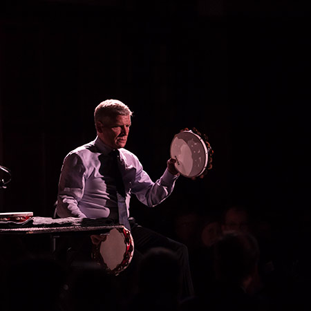 percussionist on stage with two tambourines. 