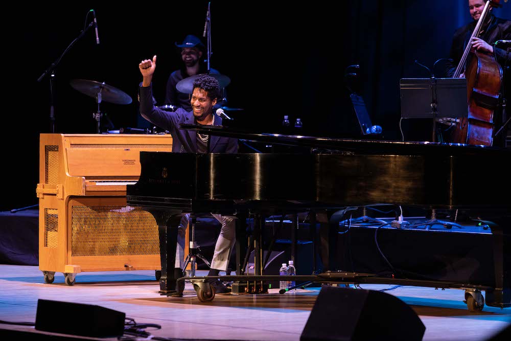 Jon Batiste seated at piano on stage