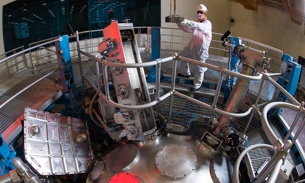 scientists in clean suits working on a laser array.