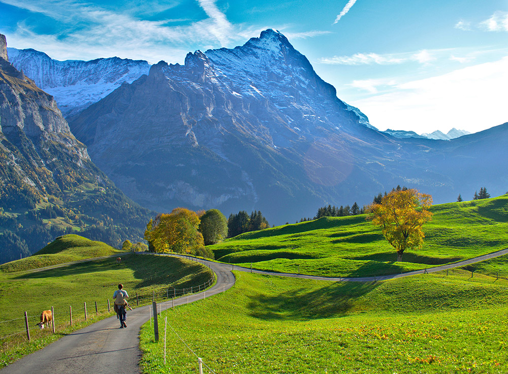 person walking along a path with mountains in the background