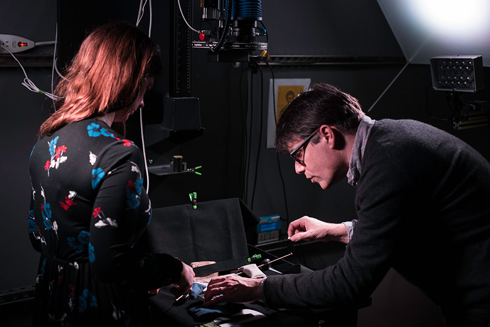 two researchers lean over a scanner in a multispectral imaging lab