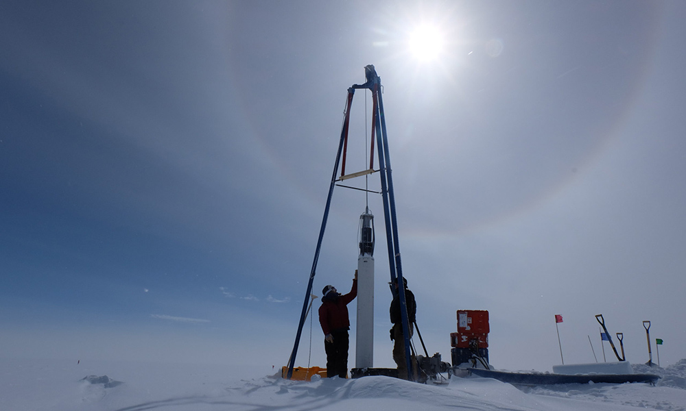 two researchers at a ice core drill in Greenland.
