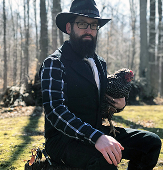 man sits outside holding a chicken.
