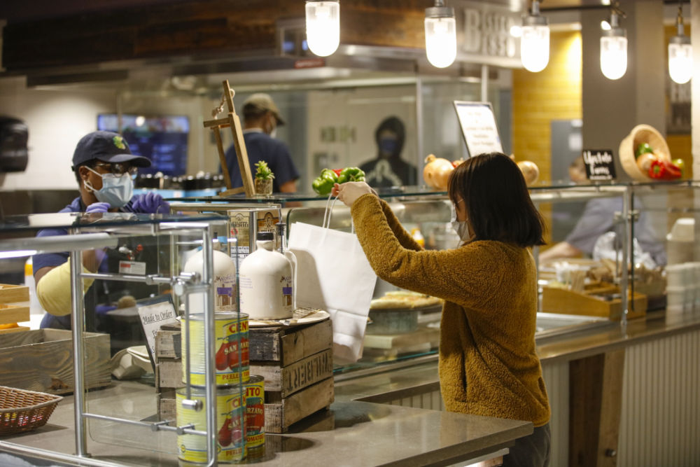 Amy Wang holds a white to-go lunch bag at one of the serving stations in Douglass Dining Center.