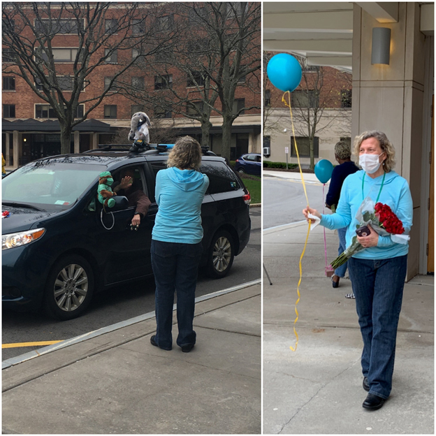 nurse in a mask holds a balloon as cars drive past the UHS building.