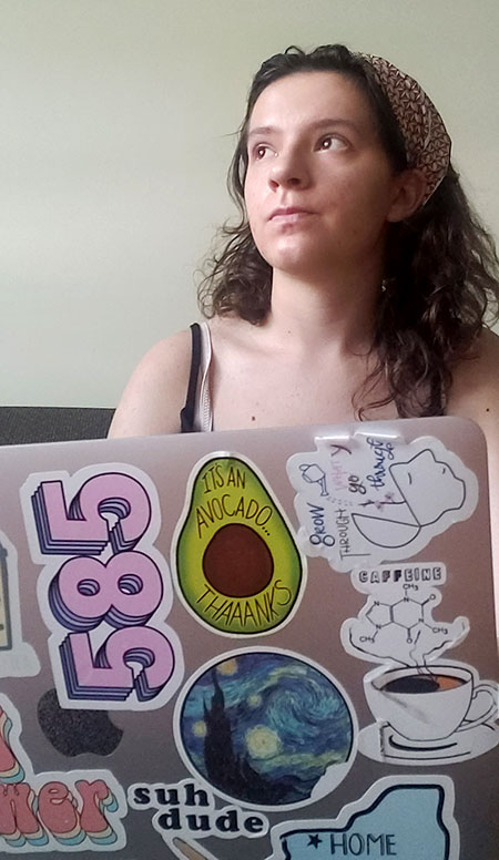 student behind her laptop, covered in stickers