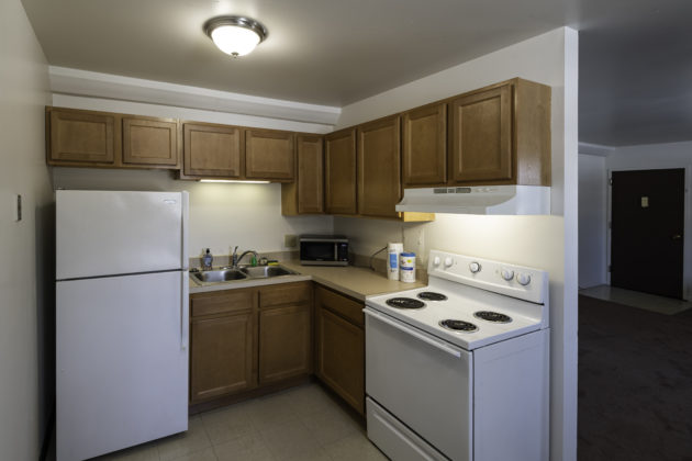 Apartment kitchen with refrigerator, sink, stove, and cabinets.