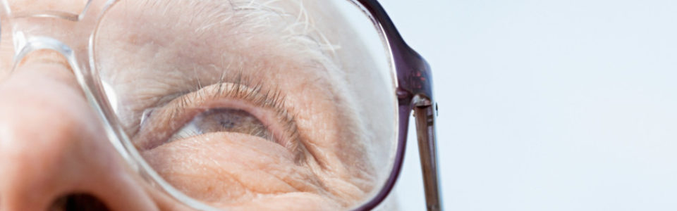 Senior man, wearing glasses and looking up, suffering from macular degeneration