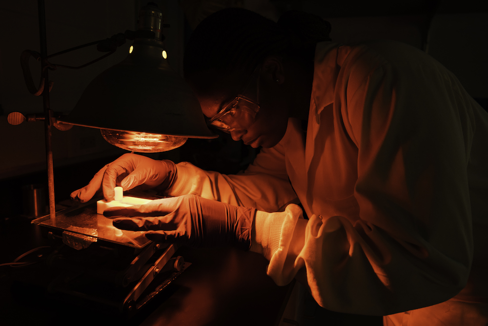 student lit by a red glow working in a lab