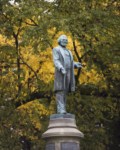 Frederick Douglass statue amid fall foliage.