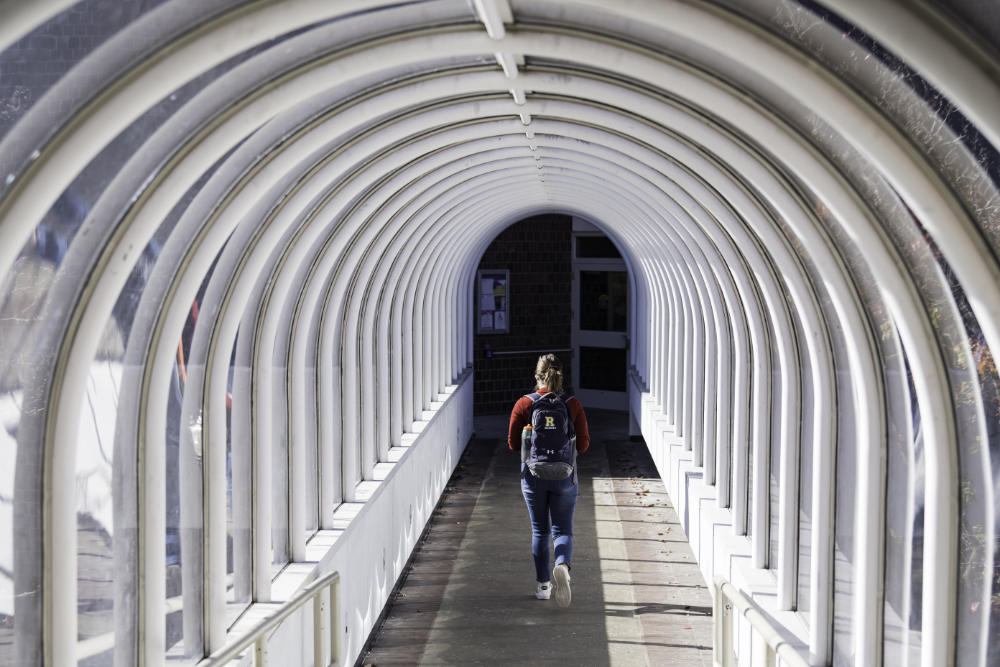 Student with a backpack photographed from behind walks through a tunnel.