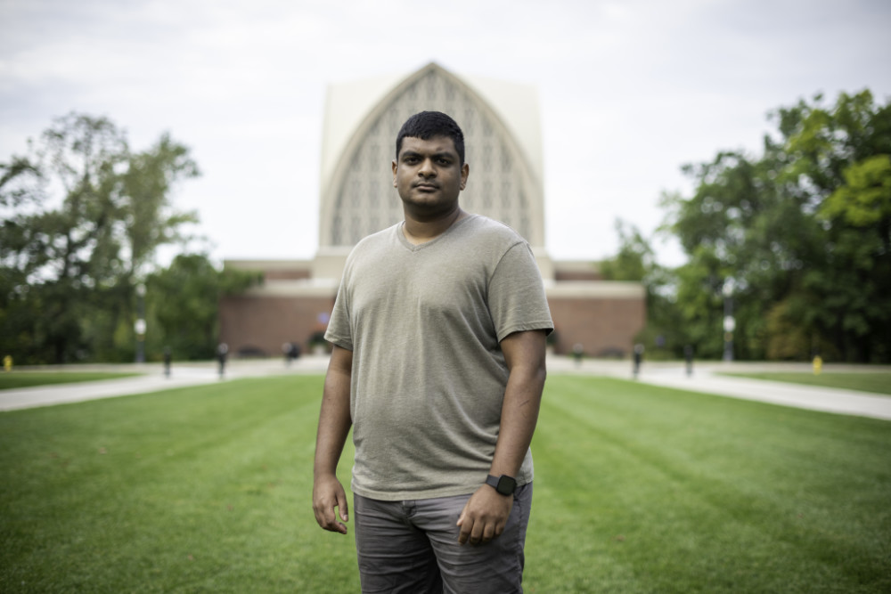 Graduate student stands in front of Interfaith Chapel with services to address the mental health of college students.