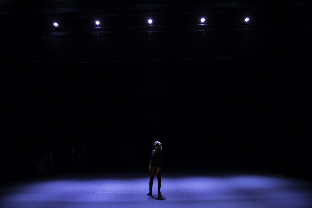 person standing in the middle of a dark stage