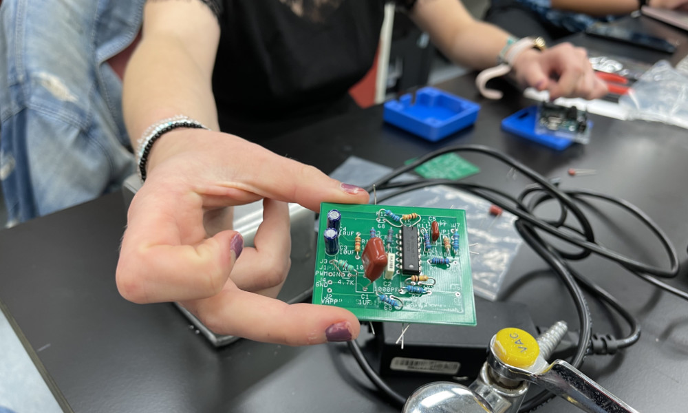 Student's hand holds part of an innovative sepsis diagnosis device.