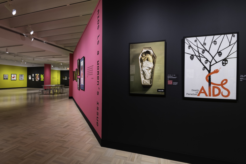 HIV/AIDS posters on display against black, pink, and yellow walls. 