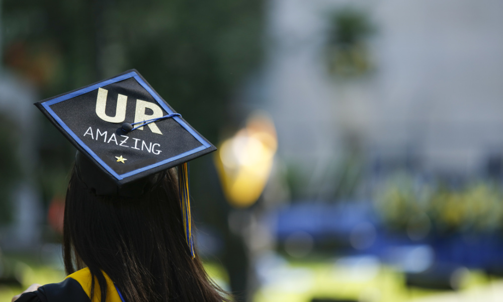 Woman facing away from camera with graduation cap mortarboard that says 