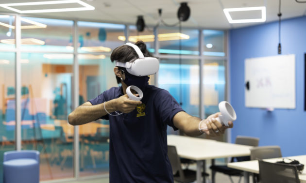 Student in extended reality headset and gear in the Studio X space.