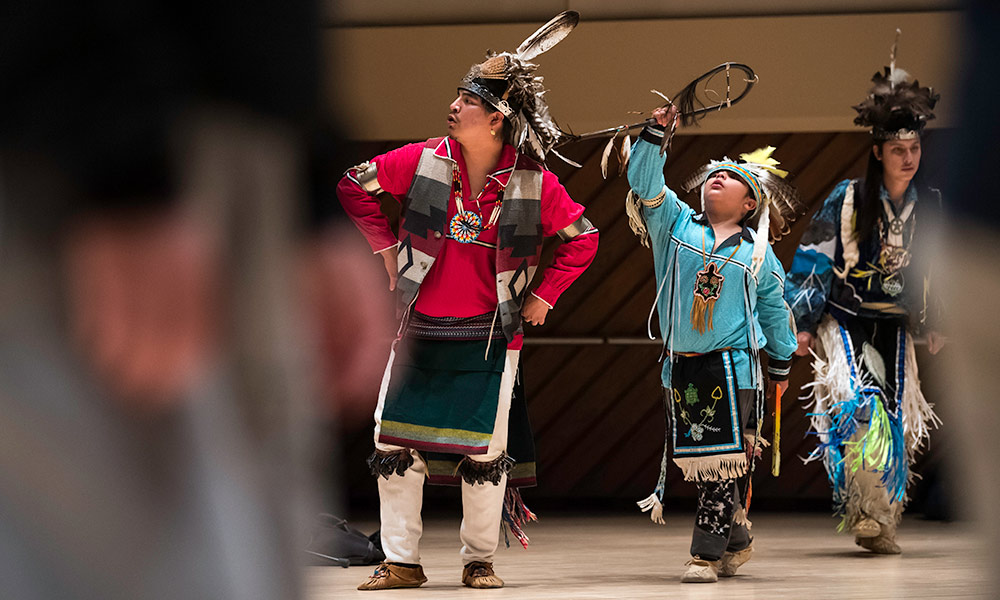Two dancers, one an adult and one a child, dressed in traditional Native American dress perform in Wilson Commons.