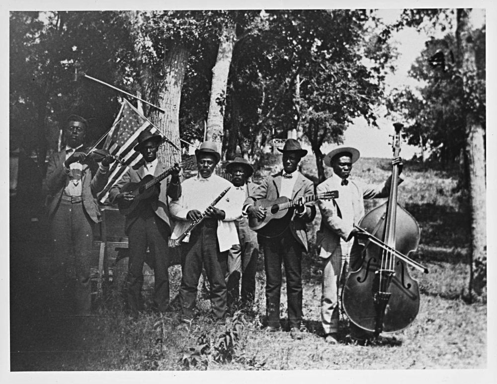 Black-and-white image of six Black men with instruments circa 1900.