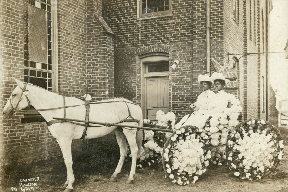 Black and white photo of two Black women dressed up in a decorated carriage for Juneteenth celebration.