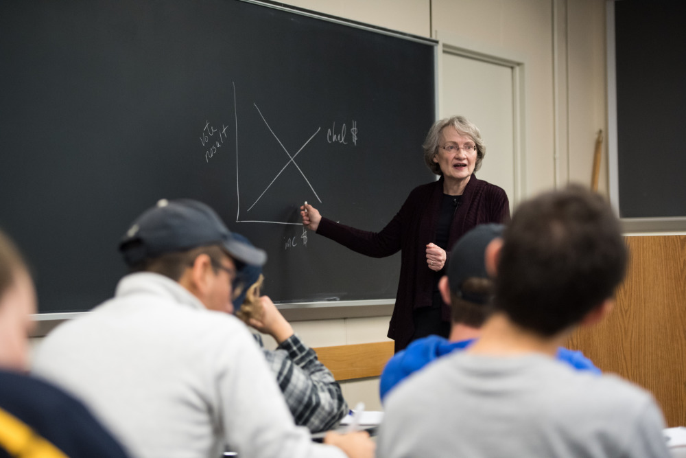 Lynda Powell at the blackboard in a classroom of students.