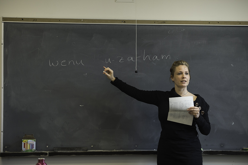 Nadine Grimm in classroom at blackboard with Bantu writing on it.