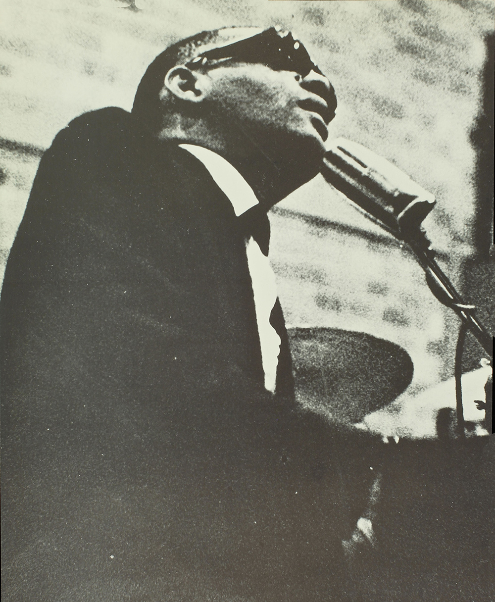 archival photo of Ray Charles singing at the piano.