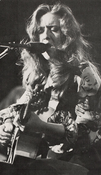 close-up concert photo of Bonnie Raitt with guitar.