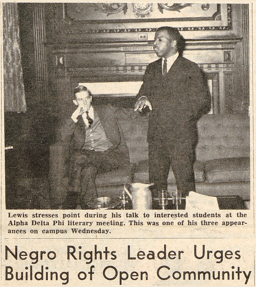 a newspaper clipping from 1964 features a photo of John Lewis standing a student as a student in the background sits and listens. The headline reads NEGRO RIGHTS LEADER URGES BUILDING OF OPEN COMMUNITY.