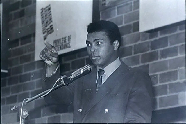 Muhammad Ali speaking from behind the podium at the Palestra.