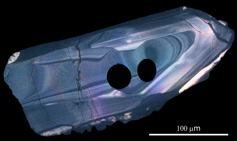 Microscopic image of a zircon crystal with two round holes. 