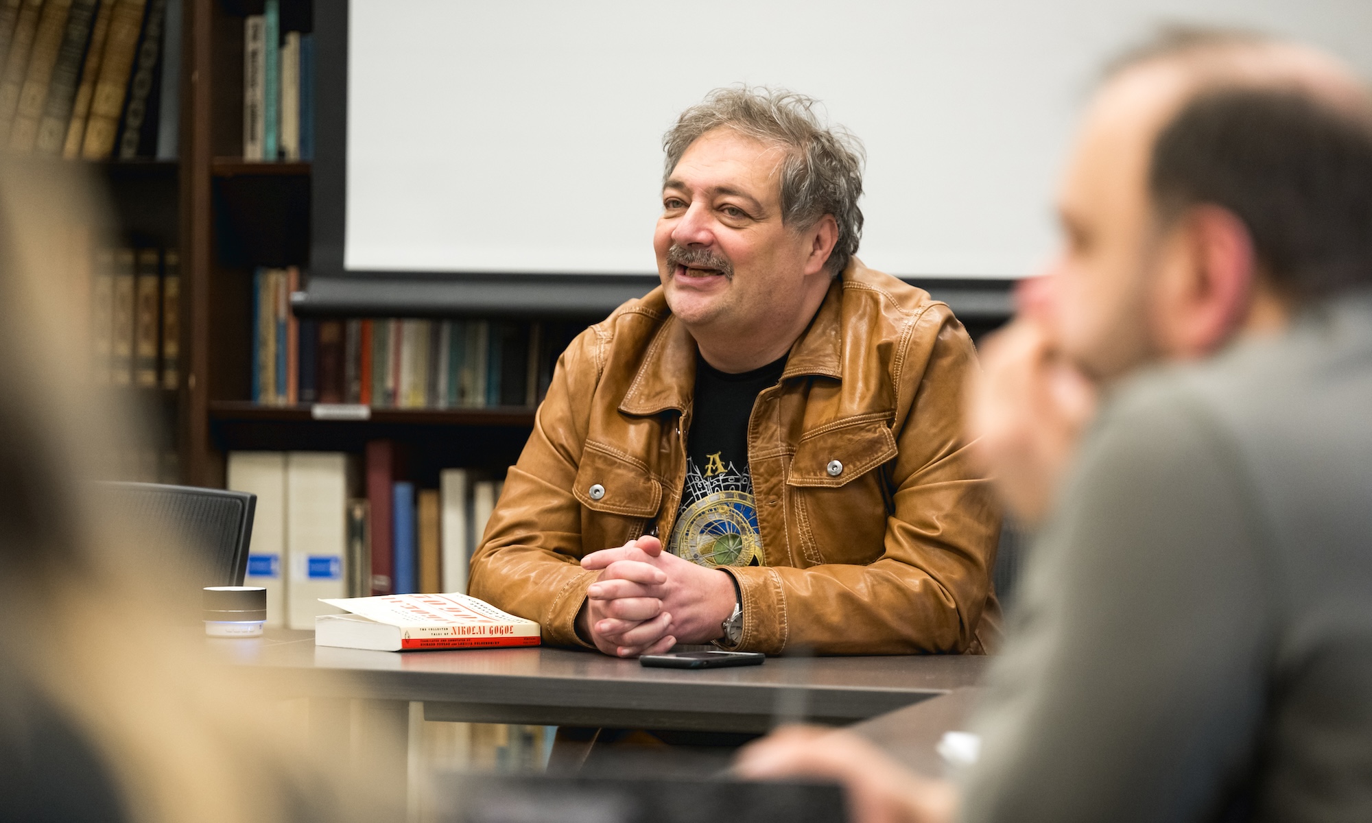 Bykov smiling while seated at seminar table with students seated around him.