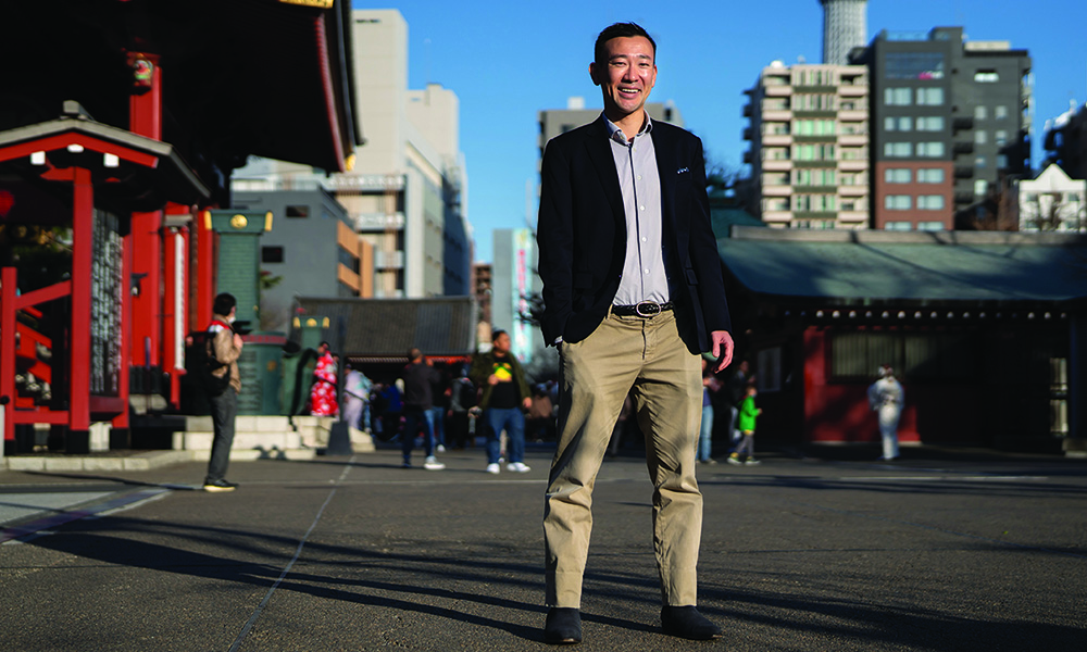 Yohay Wakabayashi in khakis and suit jacket standing in busy Tokyo plaza.
