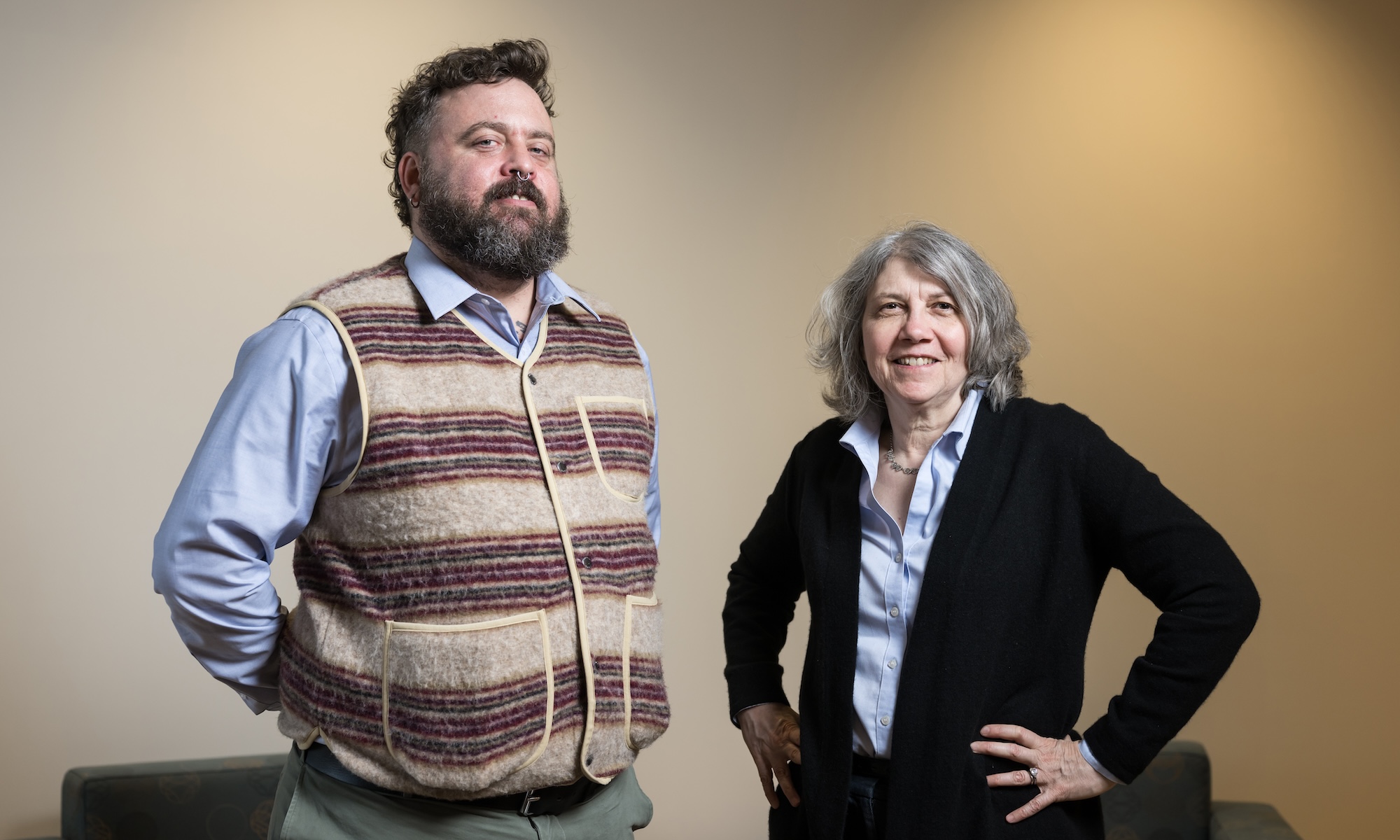 Peter Christensen and Lainie Ross standing next to each other against lit wall.