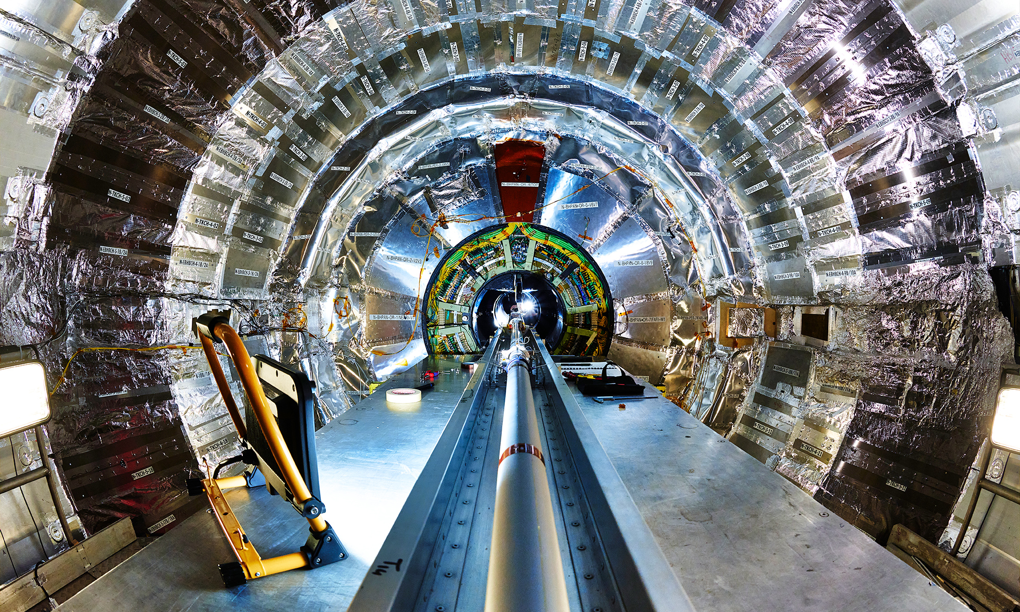 The inside of the CMS detector at CERN, showing a large central beam pipe surrounded by a silver cylinder of detectors.