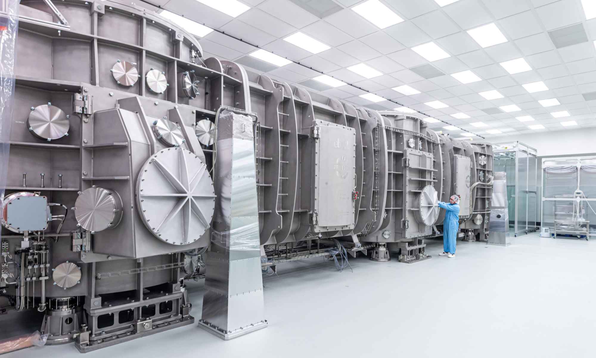 Wide shot of the compressor for generating laser pulses at ELI Beamlines to investigate the feasibility of producing coherent gamma rays. A person in safety gear stands near the instrument.