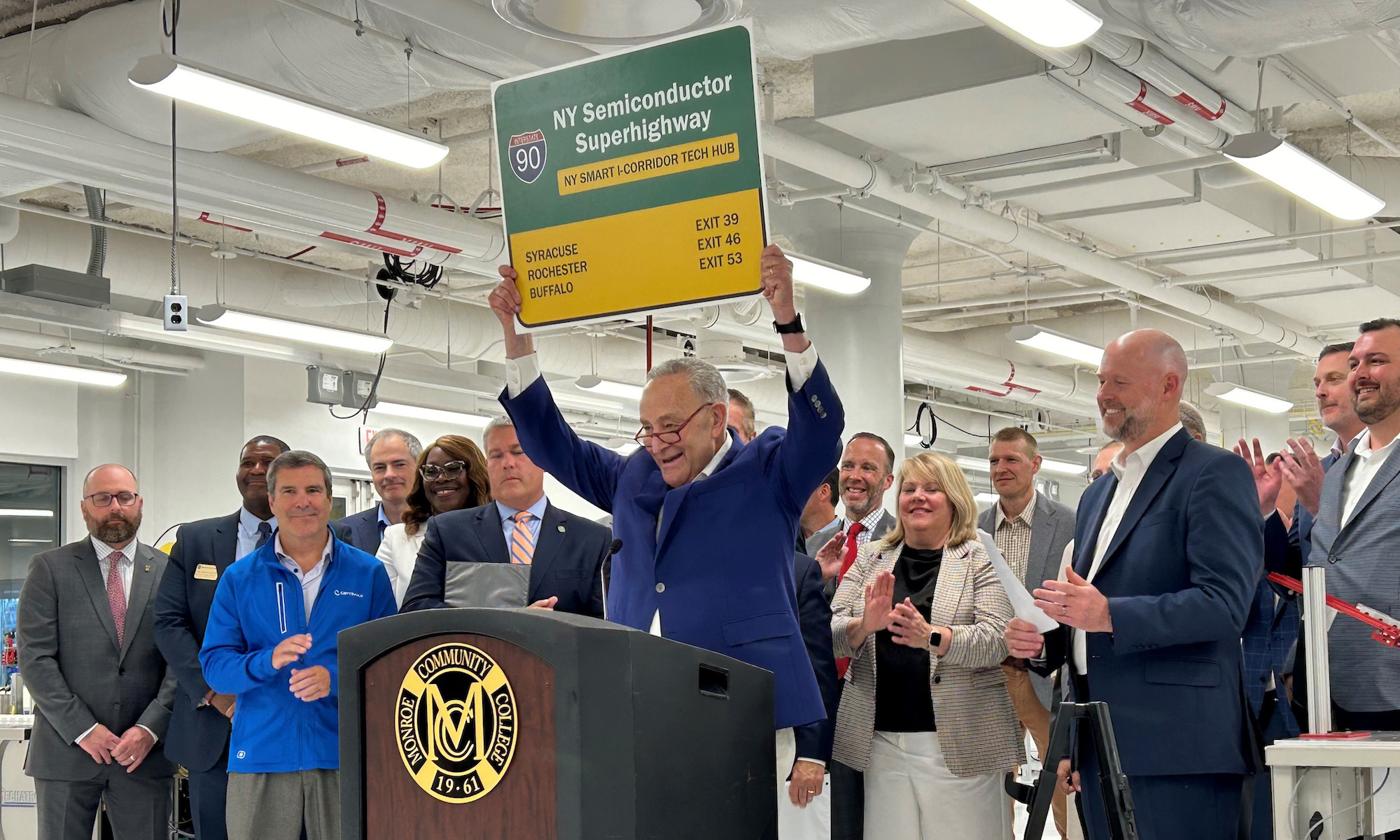 Senator Schumer, in front of other leaders, holds sign that says Route 90, "NY Semiconductor Superhighway."