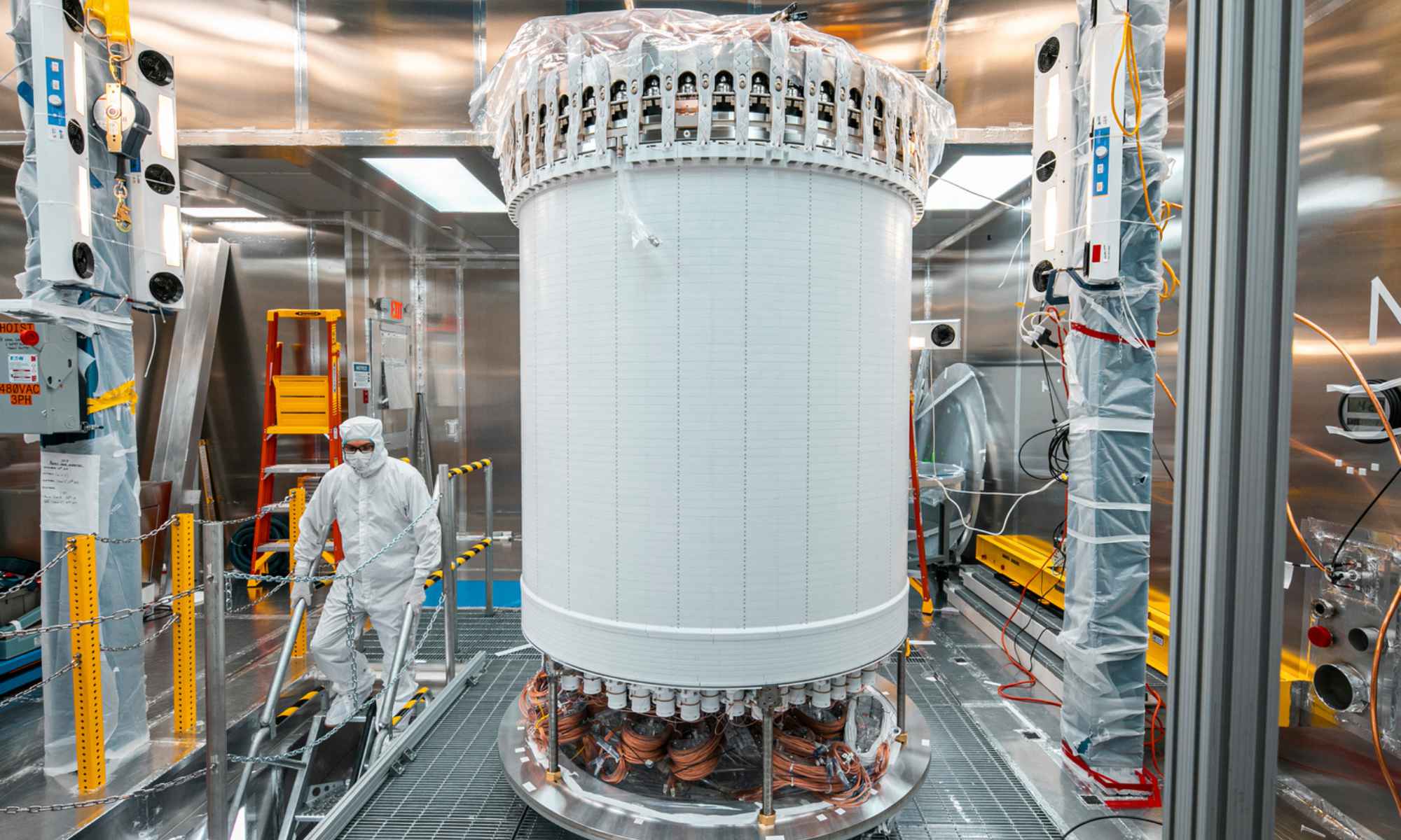 A person in a cleanroom suit walks past the LUX-ZEPLIN central detector, used to detect weakly interacting massive particles, known as WIMPs.