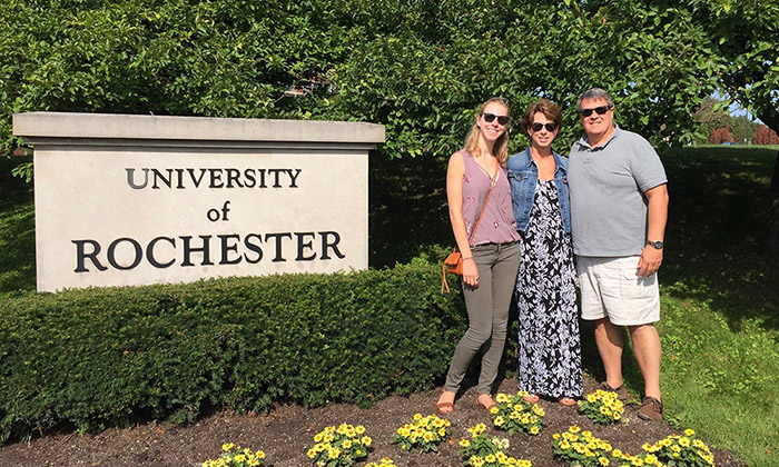 A student with her parents in front of University of Rochester sign