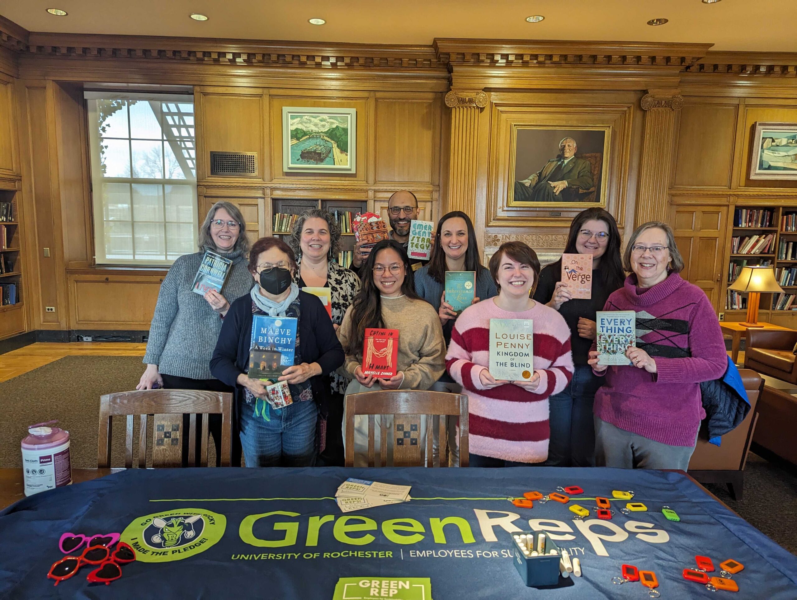A group of University of Rochester employees at a Green Reps event, each holding up a sustainability-related book
