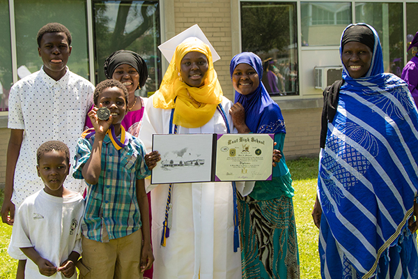 Graduate showing diploma surrounded by family