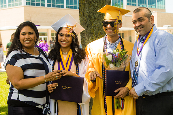 Two graduates in cap and gown with parents