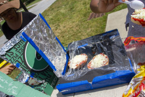 Two bagel pizzas cooking in their solar pizza box ovens.