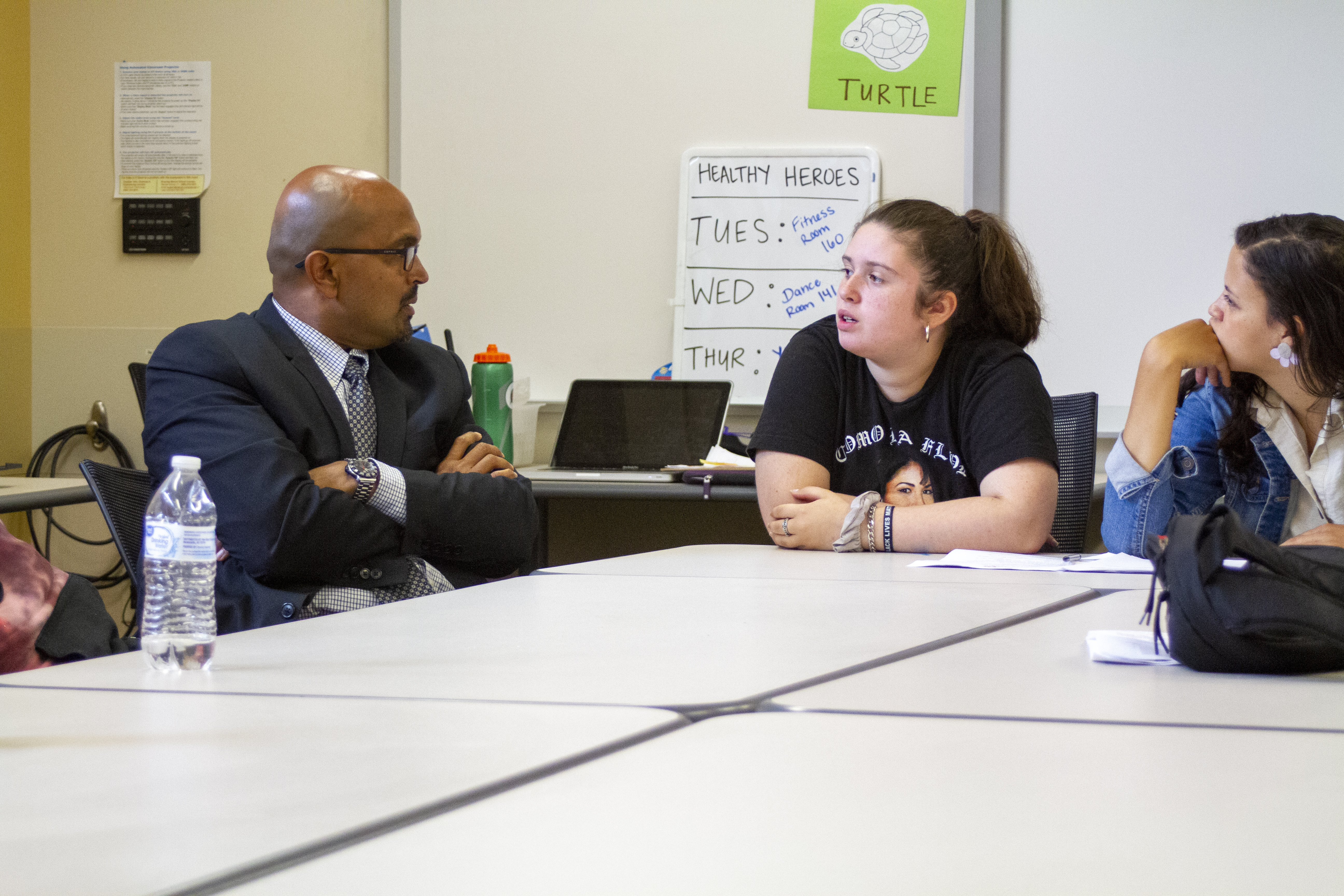 The Dean of the Warner School speaking with a young student at a table in the classroom