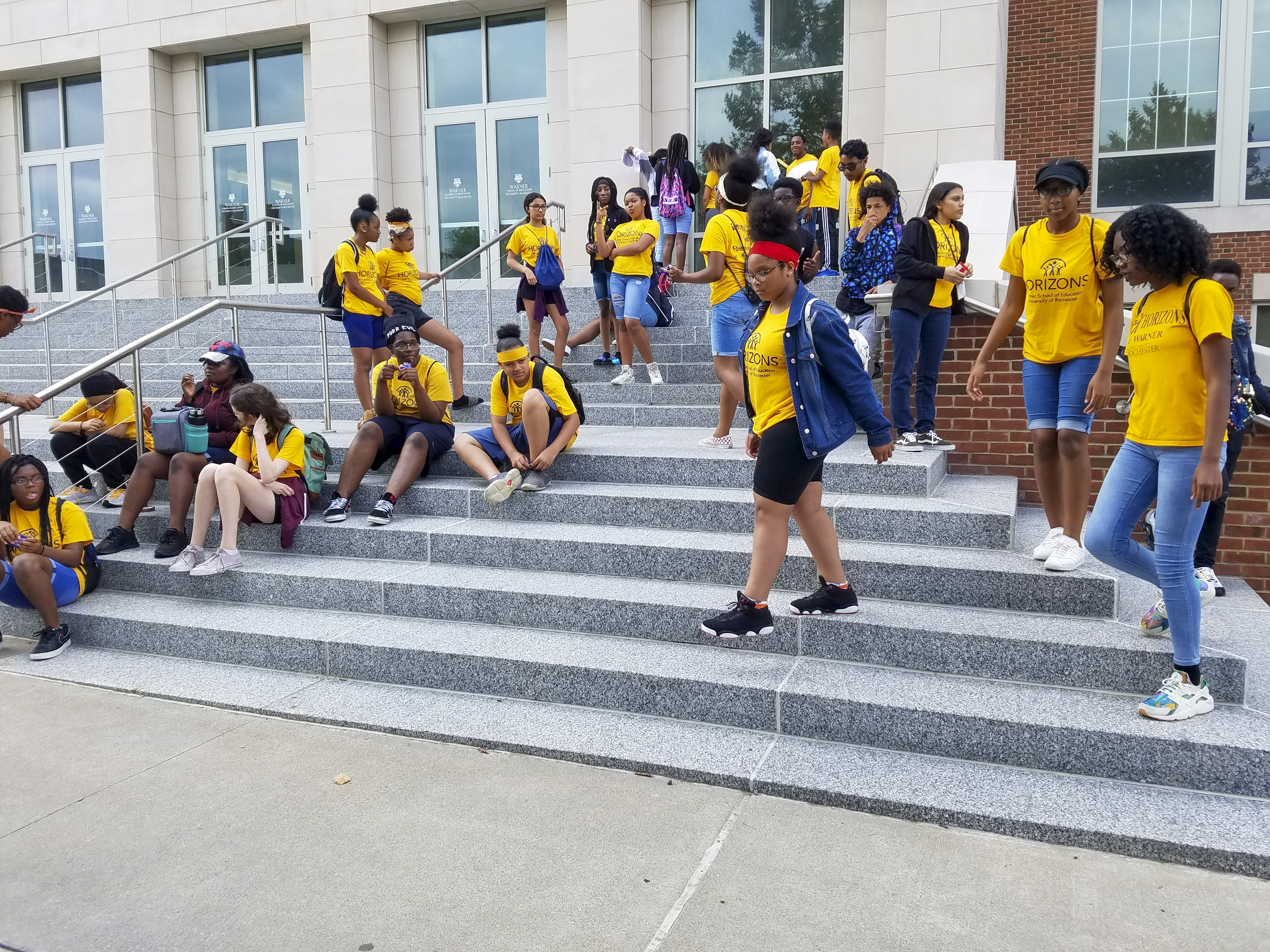 Horizons students in yellow tshirts mingling on the stairs in front og LeChase Hall before their field trip.